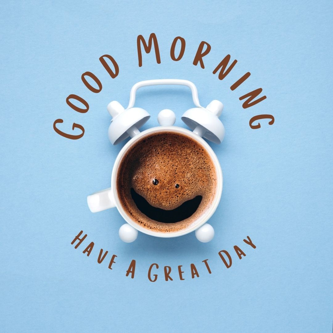 A creative image featuring a cup of coffee with a smiling face in the foam, simulating the top part of an alarm clock with the text "Good Morning, Have a Great Day" on a blue