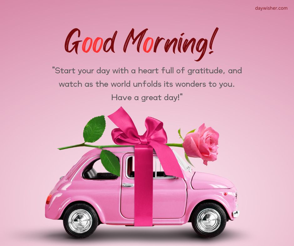 A pink miniature car with a large pink rose on its roof against a pink background. The text "Have a Great Day" is displayed above a quote about starting the day with gratitude.
