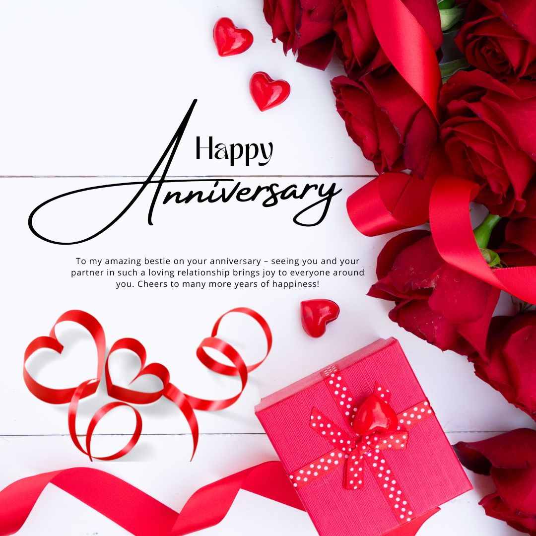 Anniversary greeting card with text "Wedding Anniversary Wishes For Friends" surrounded by red roses, a red ribbon shaped into a heart, and a pink gift box on a white wooden surface.