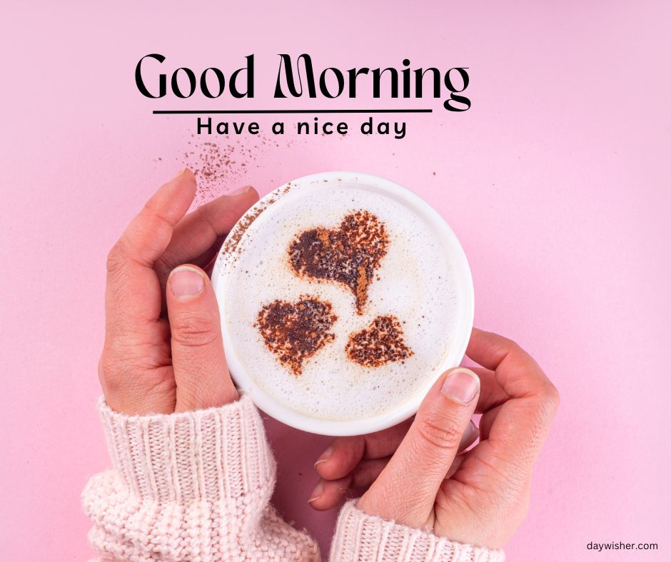 Hands holding a cup of coffee with "good morning" text and three heart shapes in the froth, on a pink background, perfect for good morning images.