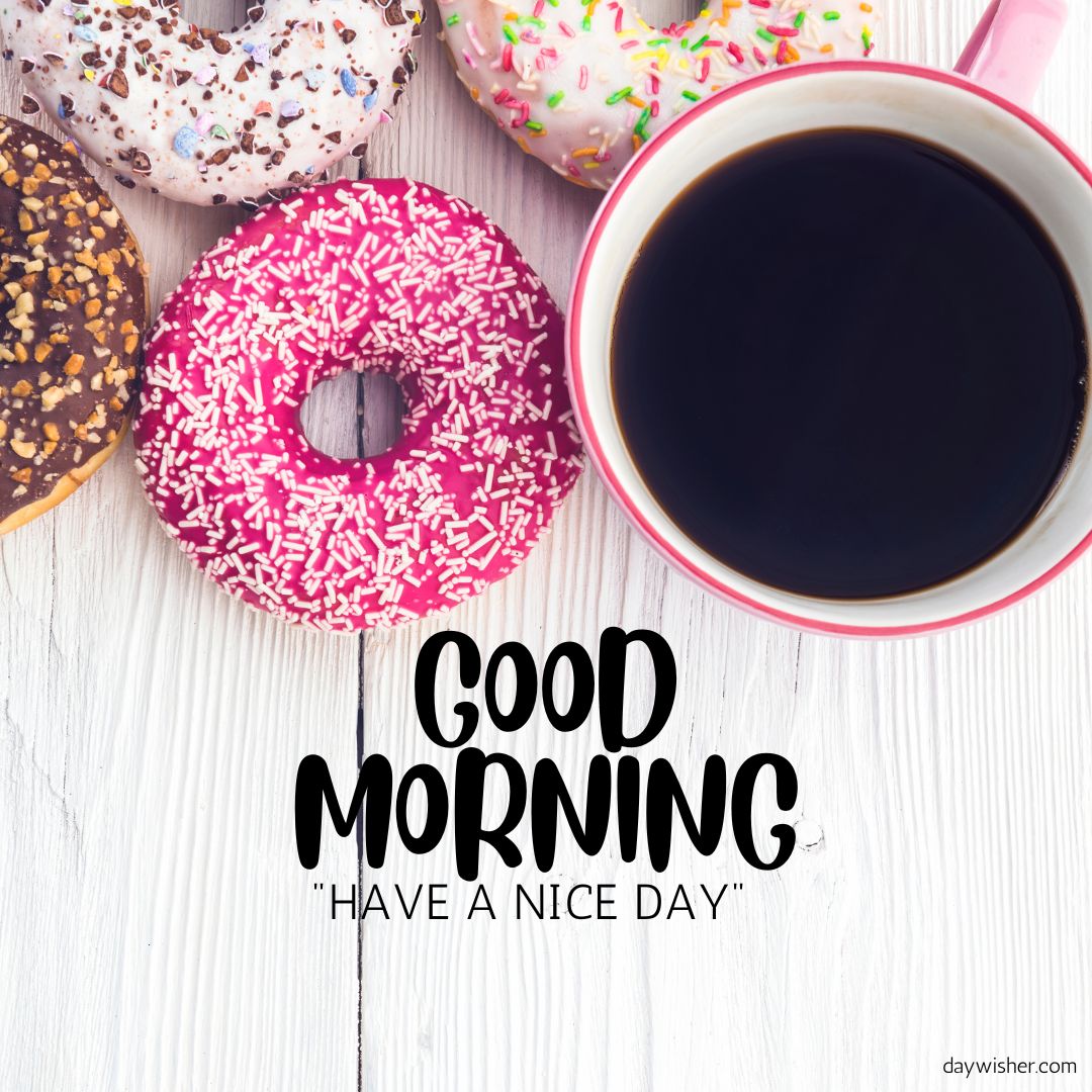 A morning setup featuring a cup of black coffee and colorful donuts with various toppings, alongside a "good morning - have a nice day" text, on a wooden surface.
