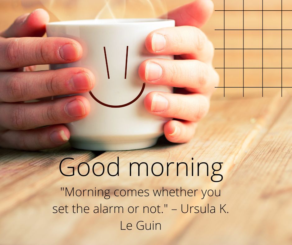 A person holding a white coffee mug with a smiling face; the background features wooden texture and a "Good Morning" quote by Ursula K. Le Guin.