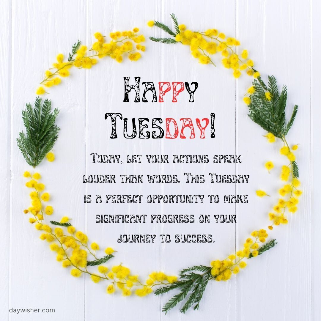 Image of a floral wreath made of yellow mimosa flowers and green leaves forming a circular border on a white wooden background. Inside it, the text reads "Happy Tuesday Blessings!" followed by an