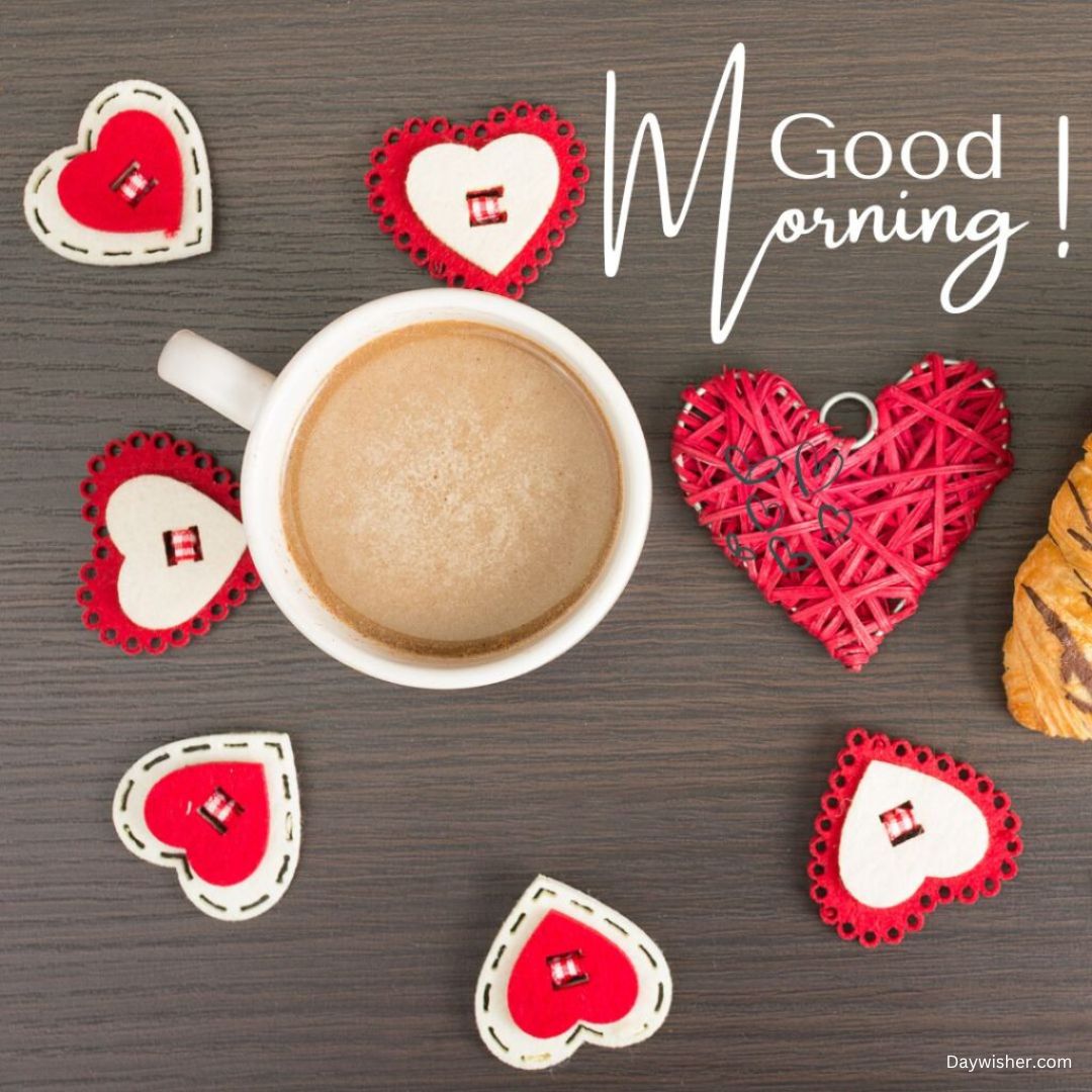 A cup of coffee surrounded by various decorative red and white hearts with a "Good Morning Love" text, displayed on a dark wooden surface.