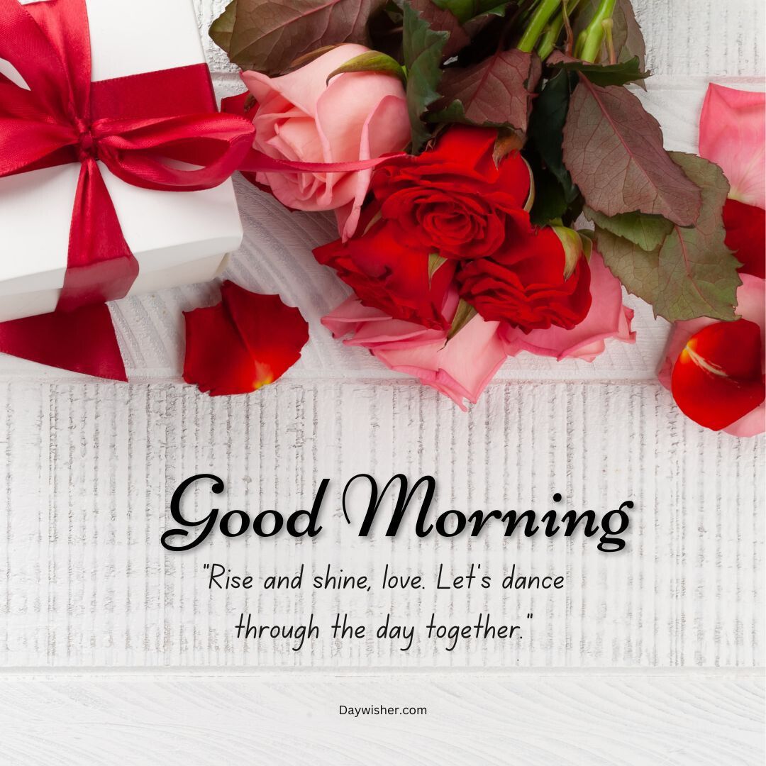 A beautifully arranged greeting image featuring a bright red rose, petals, and a gift wrapped in white and red ribbon on a textured surface. The text says, "Good Morning Love - rise and shine.