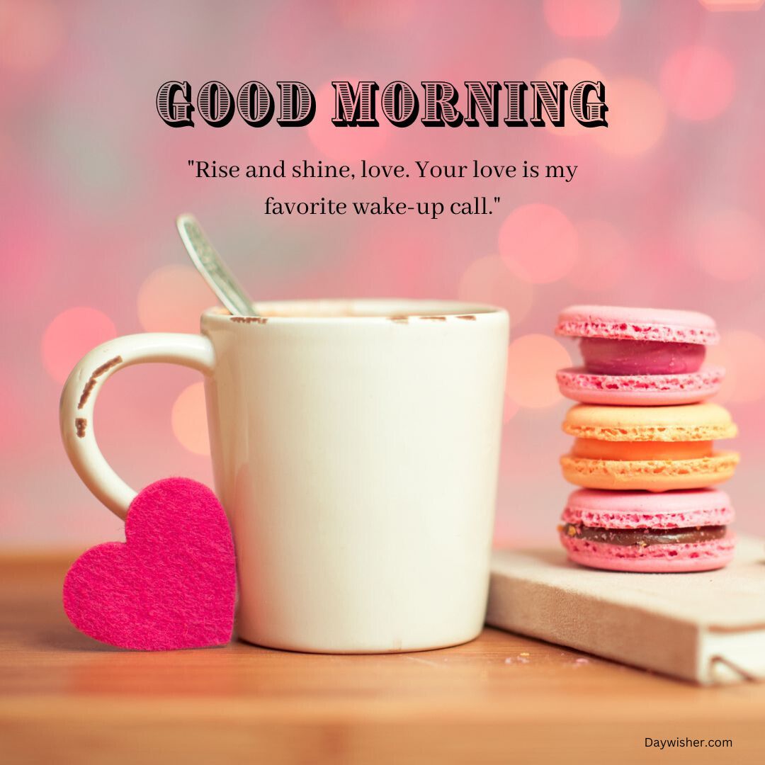 A cozy morning-themed image featuring a white mug with a small red heart, a stack of colorful macarons, all against a soft pink bokeh background with a "Good Morning Love" greeting.
