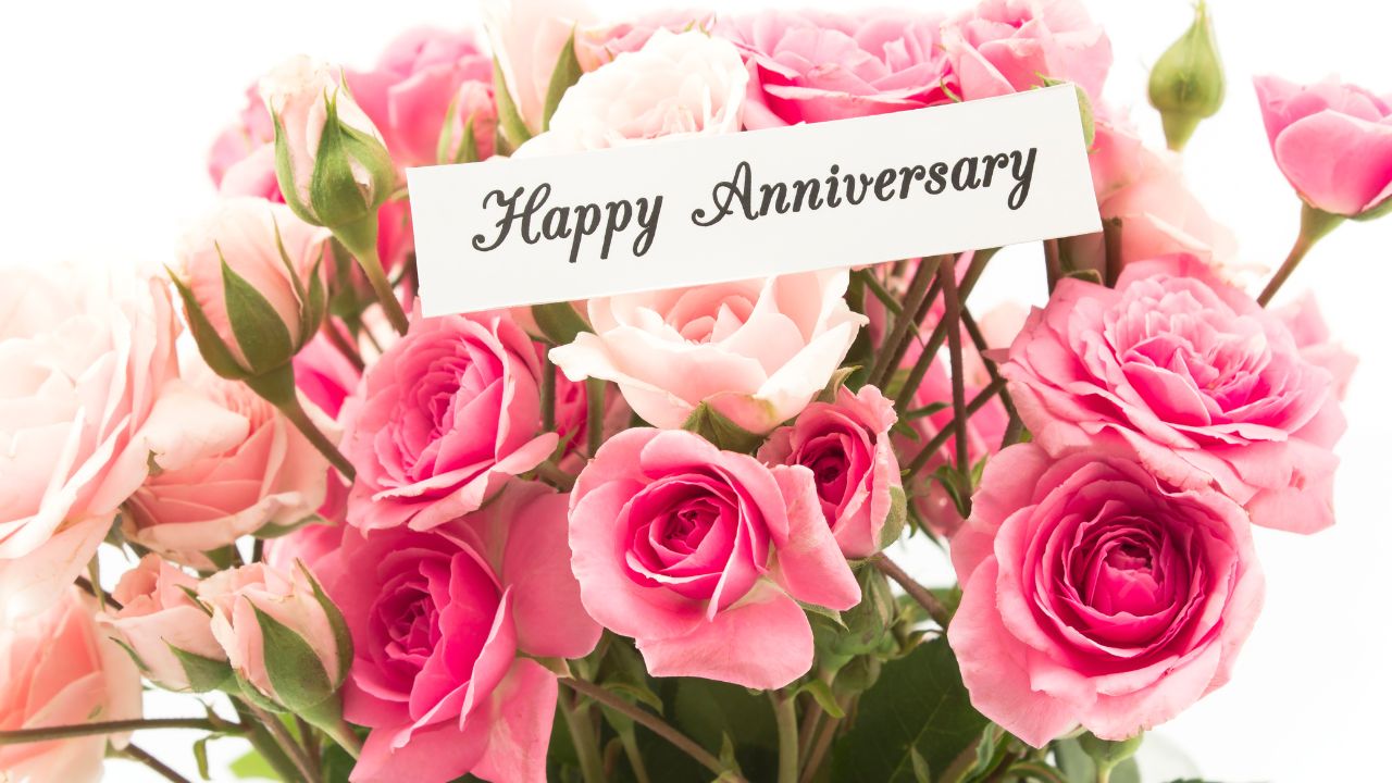A vibrant bouquet of pink roses with a small tag reading "wedding anniversary wishes for wife" in the center, set against a white background.