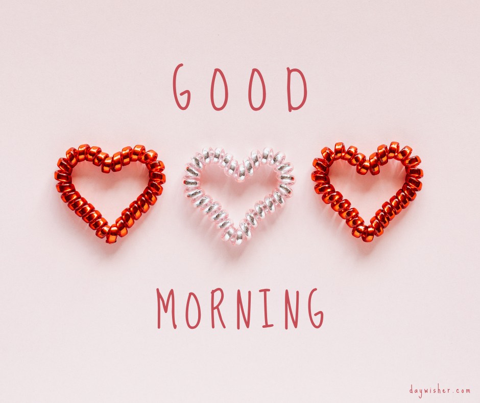 A charming good morning heart image featuring three beaded hearts, two red and one silver, arranged in a row on a light pink background. The text "Good Morning" is written above and below the hearts in a playful font. This delightful and simple image is perfect for sending cheerful and loving morning greetings.