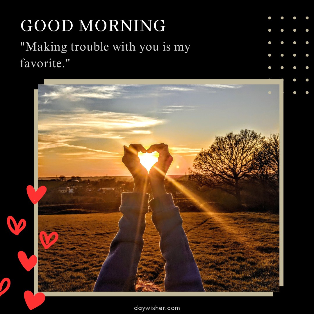 A beautiful good morning heart image featuring hands forming a heart shape with the sun shining through at sunrise. The background showcases a scenic view of a field and trees under a vibrant sky. The text at the top reads "Good Morning" followed by the quote "Making trouble with you is my favorite." This image is perfect for sharing romantic and playful morning greetings.
