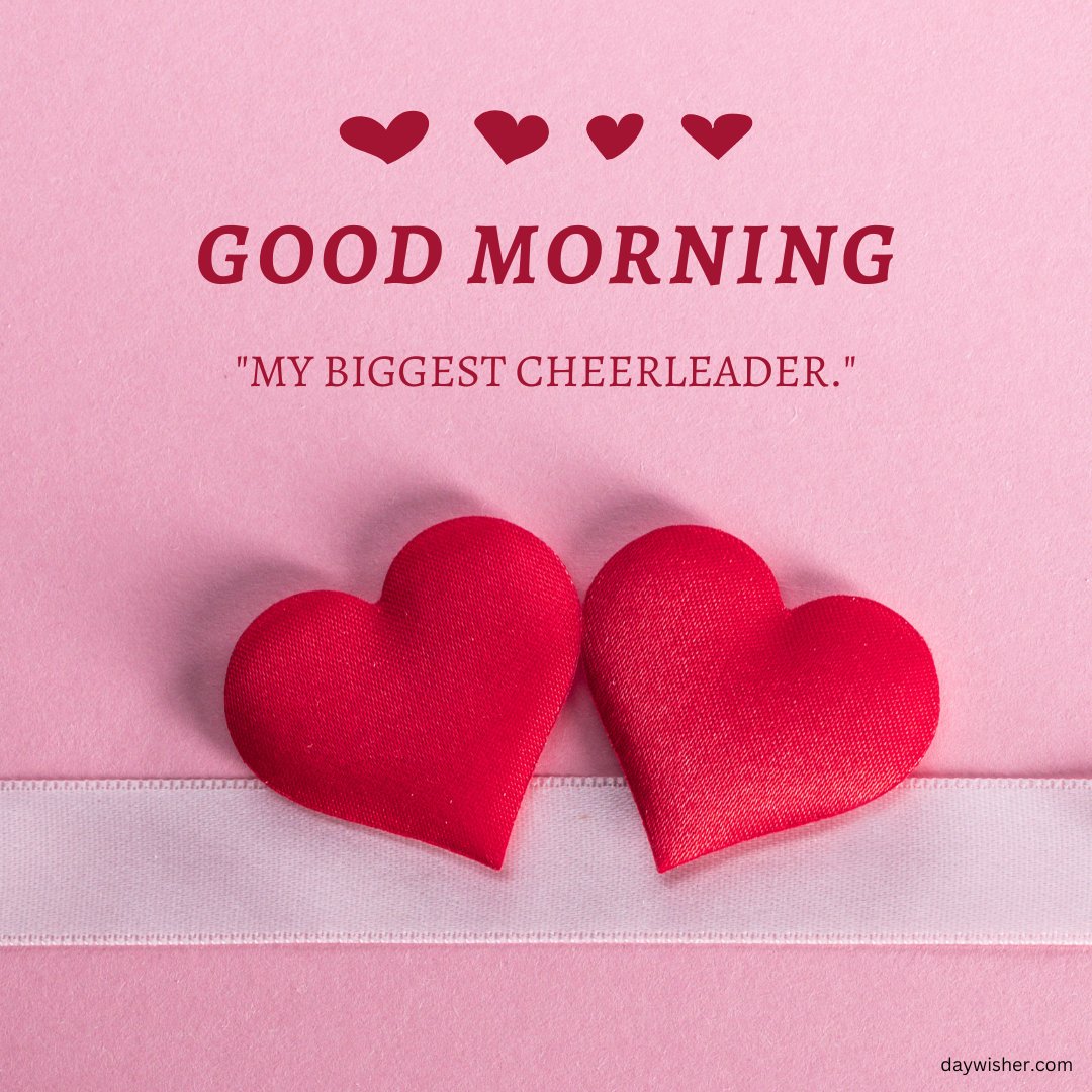 A sweet good morning heart image featuring two red fabric hearts resting on a pink background with a white ribbon. The text "Good Morning" is displayed above the hearts, accompanied by the quote, "My biggest cheerleader." This simple and heartfelt image is perfect for sending loving and supportive morning greetings.